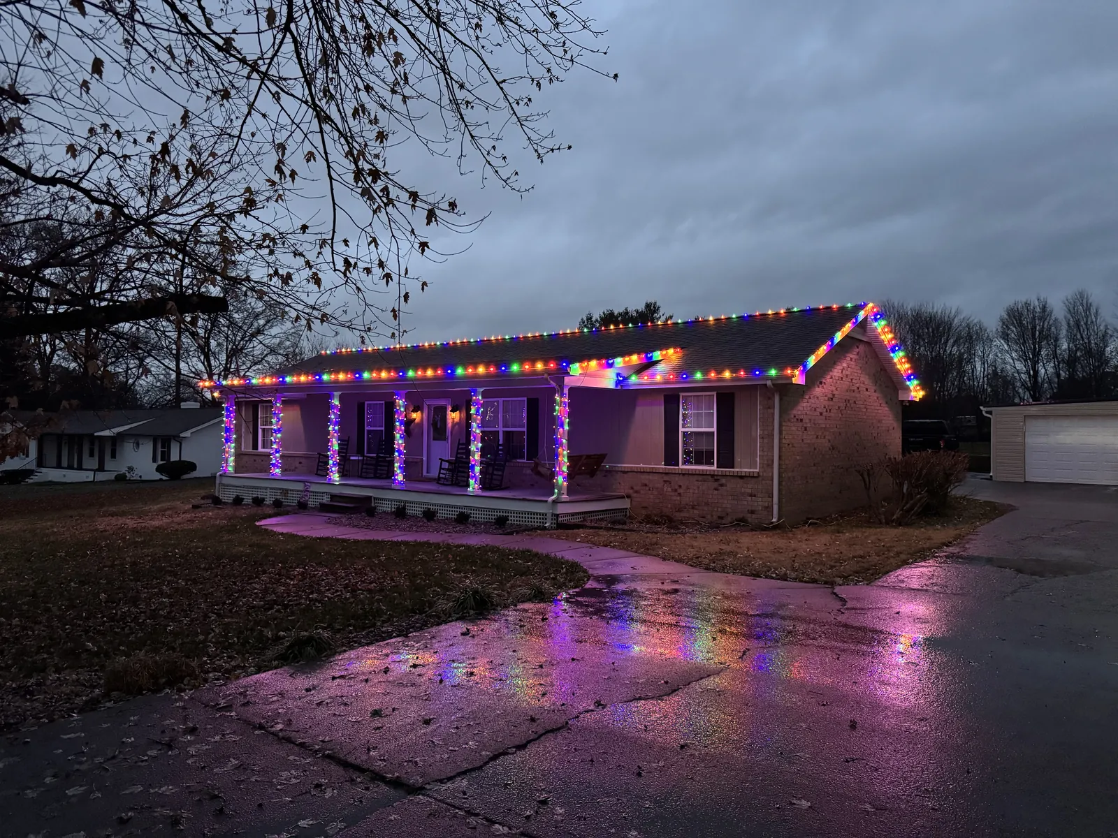 A brick ranch house in White House, Tennessee in multicolor lights, the glow reflected on a wet driveway