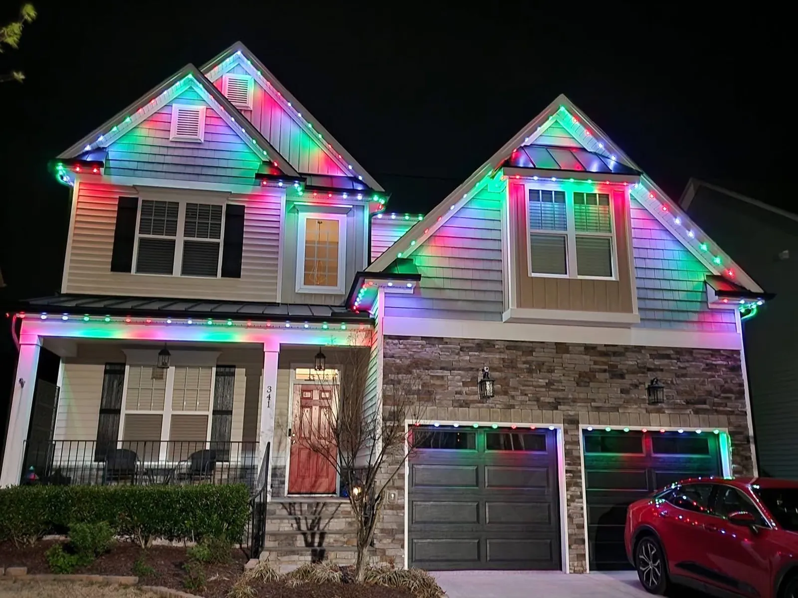 A two story home with its permanent lights set to pink and green along the rooflines and porch
