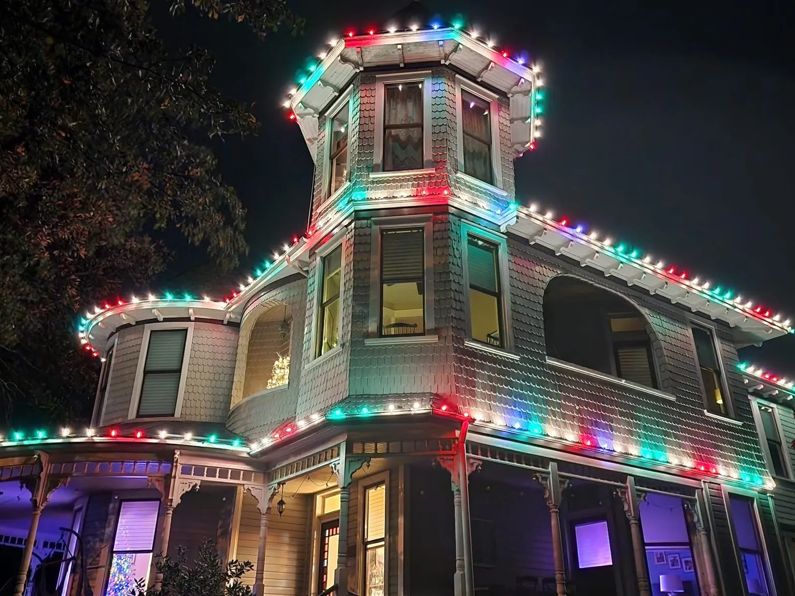 A tall Victorian house outlined in red and green, right up the turret and along the porch rails